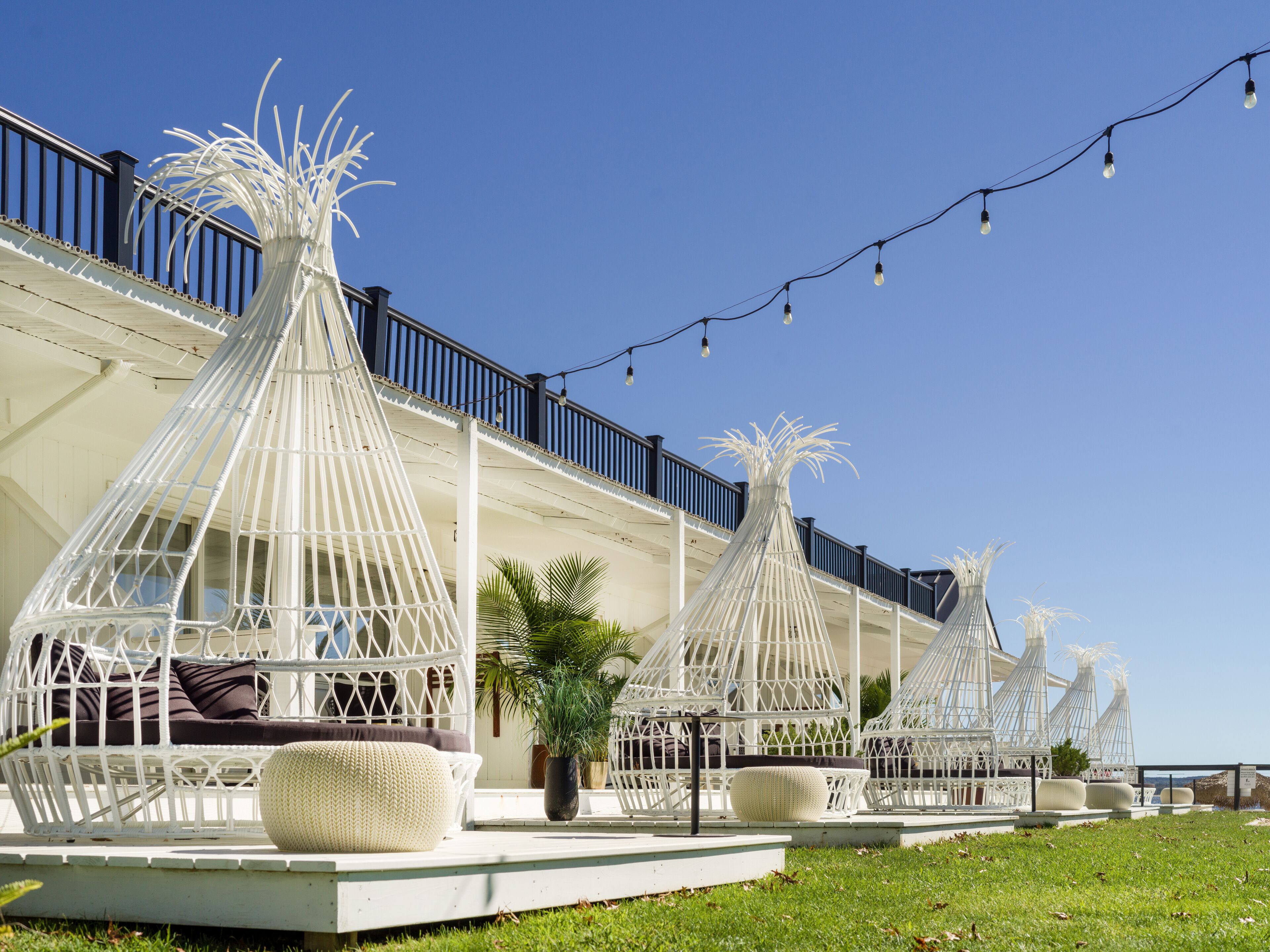 Outdoor seating areas with white wicker furniture and a clear blue sky.