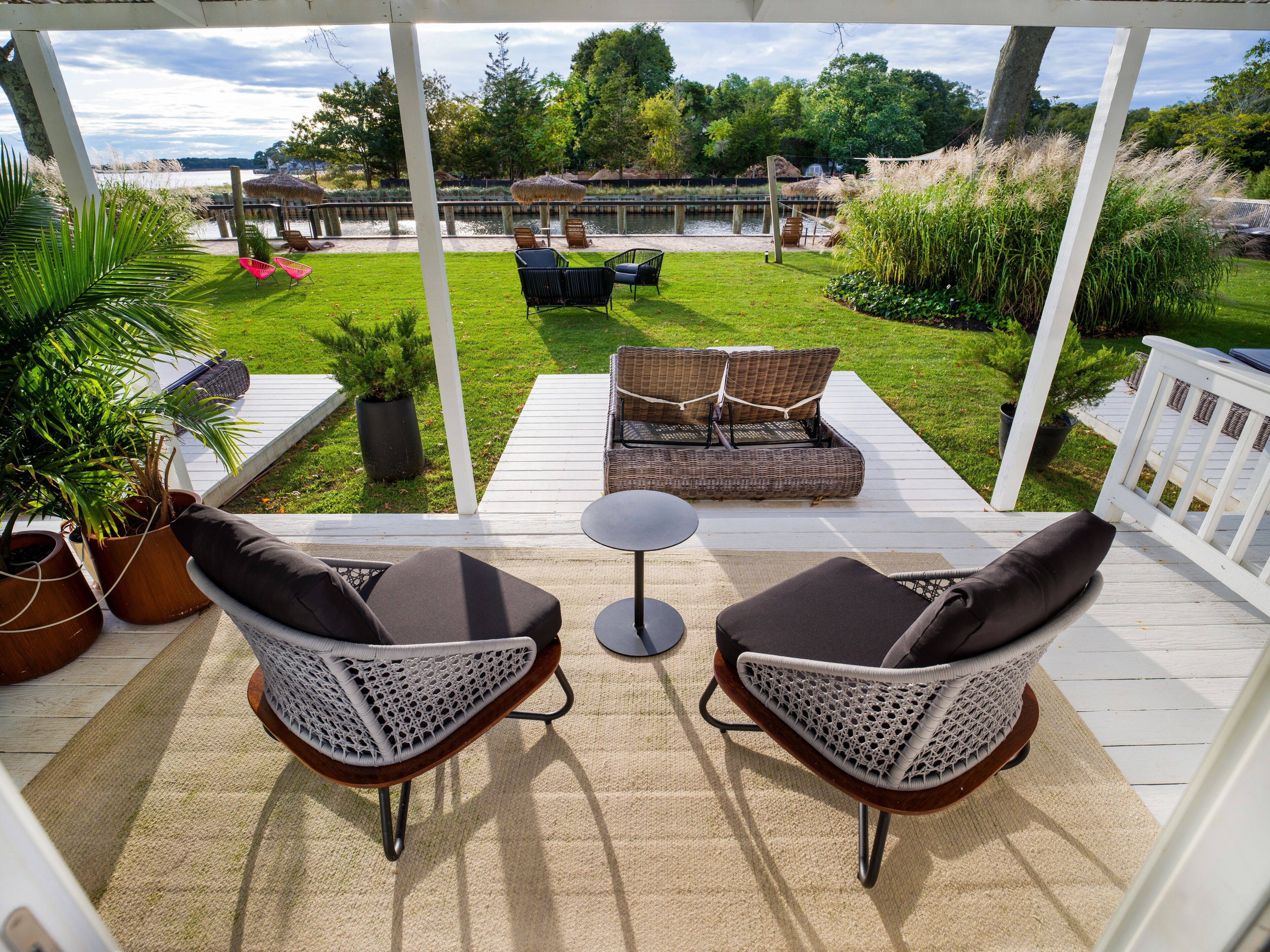 A covered patio with two wicker chairs, a small round table, and a sofa with cushions.