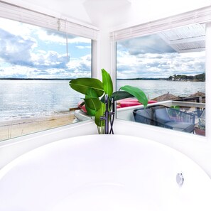 A modern room with a large window overlooking a lake, a plant, and a seating area with a view. - Aqua by American Beech - Adults Only (Riverhead)