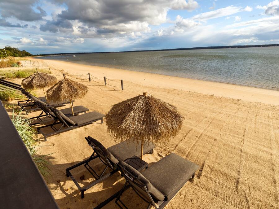 A beach with lounge chairs and thatched umbrellas.