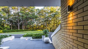 Un espacio exterior moderno con un muro de ladrillo, una planta en maceta y un césped bien cuidado.
