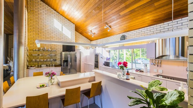 Una cocina moderna con protector contra salpicaduras de ladrillo, techo de madera y una isla grande con taburetes de bar.