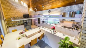 Una cocina moderna con encimeras blancas, salpicadero de ladrillo y vigas de madera en el techo.