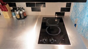 Una cocina con cocina por inducción negra, encimera de acero inoxidable y campana extractora negra.