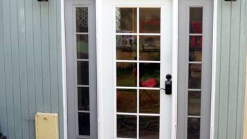 A white double door with a glass panel, a keypad lock, and a small yellow electrical box to the left.