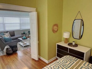 Une chambre comprenant un lit, une commode, un miroir et une porte donnant sur un balcon.