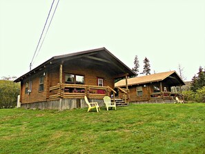 Une cabane en rondins avec une véranda et deux chaises.