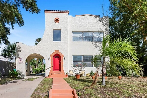 A building with a red door, a small window, and a circular window on the upper level.