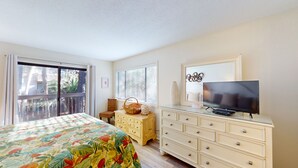 A bedroom with a bed, a dresser, a television, and a window with blinds.