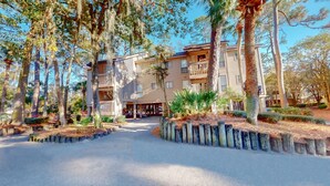 A multi-story hotel with a central courtyard, surrounded by trees and plants.