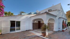 Une maison moderne dotée d’un patio carrelé, d’un garage avec portes coulissantes et d’un petit jardin.