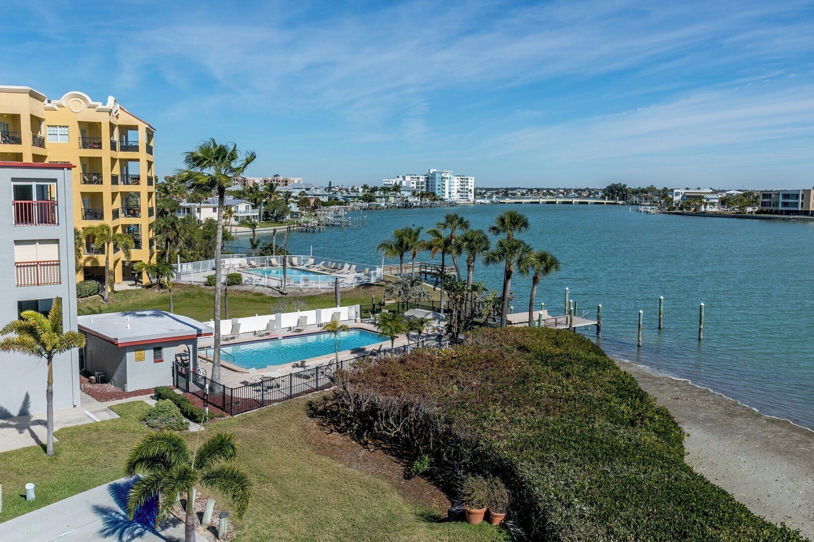 Hotel aan het water met zwembad, palmbomen en uitzicht op het water.