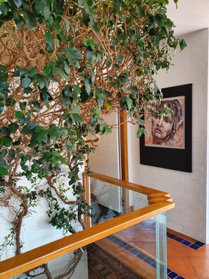 Stunning staircase leads to an upper level with a clear view of the lower floor, complemented by a large artwork and patterned tile flooring.
