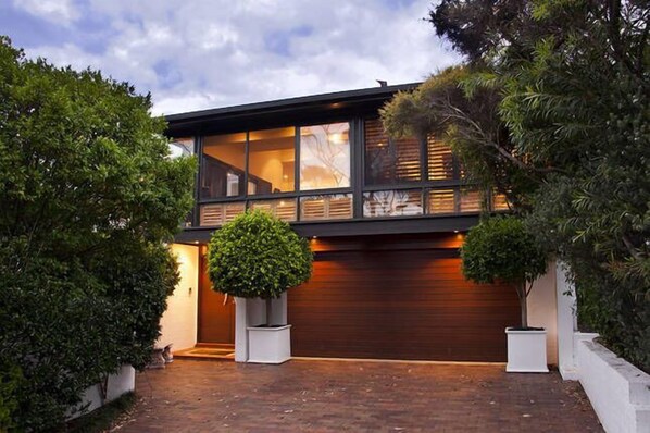 A modern two-story house with large windows, a garage, and a well-maintained garden.