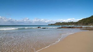 A beach with clear blue water, sandy shore, and rocky outcrops. - BANNISTER COVE MOLLYMOOK - Art House - spa - (Mollymook Beach)