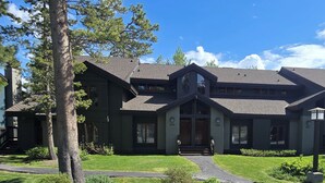 A two-story house with a dark exterior, a prominent front porch, and a well-maintained lawn. - Snowcreek Resort Vacation Rental 456 (Mammoth Lakes)