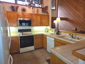 A kitchen with wooden cabinets, a microwave, an oven, a dishwasher, and a sink.