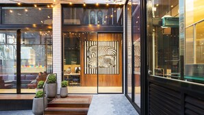 Une entrée moderne avec une porte en verre, une fresque représentant des zèbres et des sièges à l’extérieur.