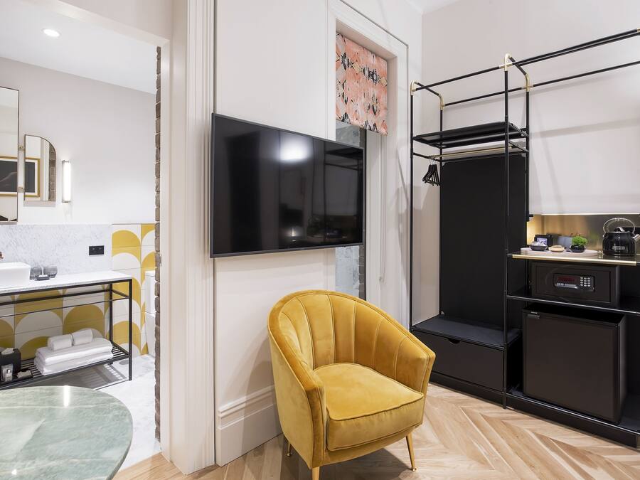 A modern bathroom with a large mirror, a sink, and a yellow armchair.