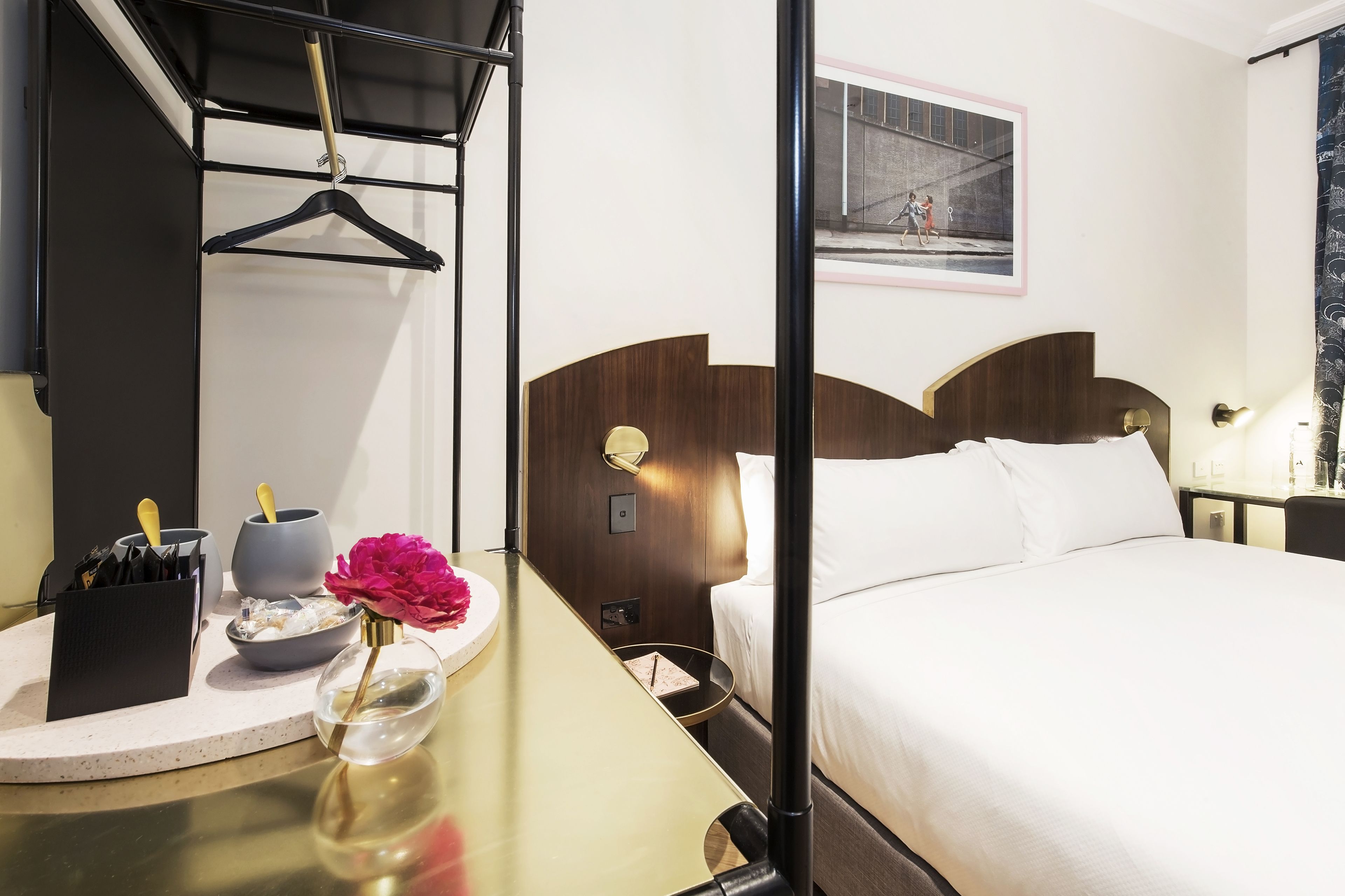 Habitación de hotel con cama, mesita de noche y espejo.