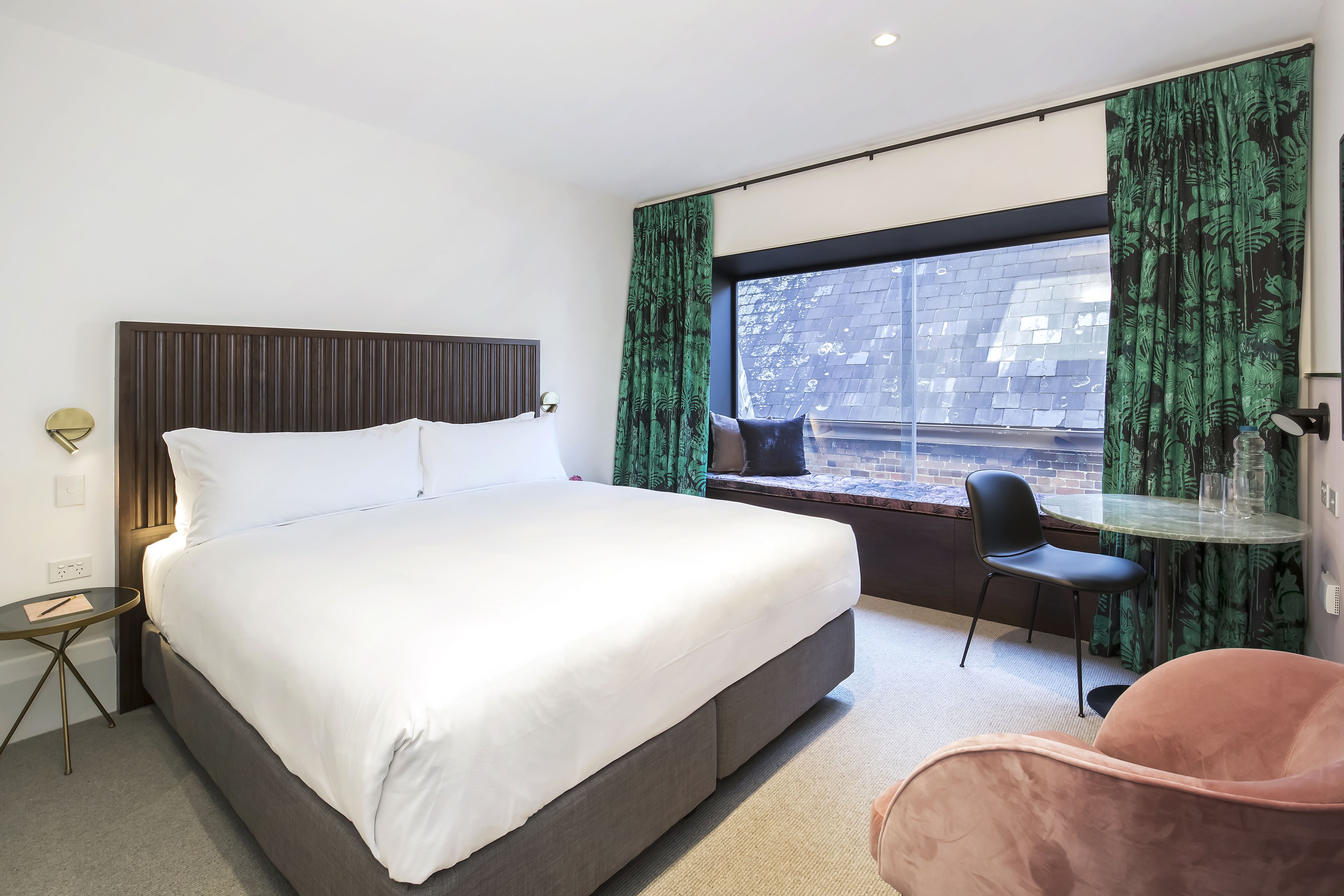 Camera d'albergo moderna con un letto grande, un tavolino rotondo, una sedia e vista sull'esterno.