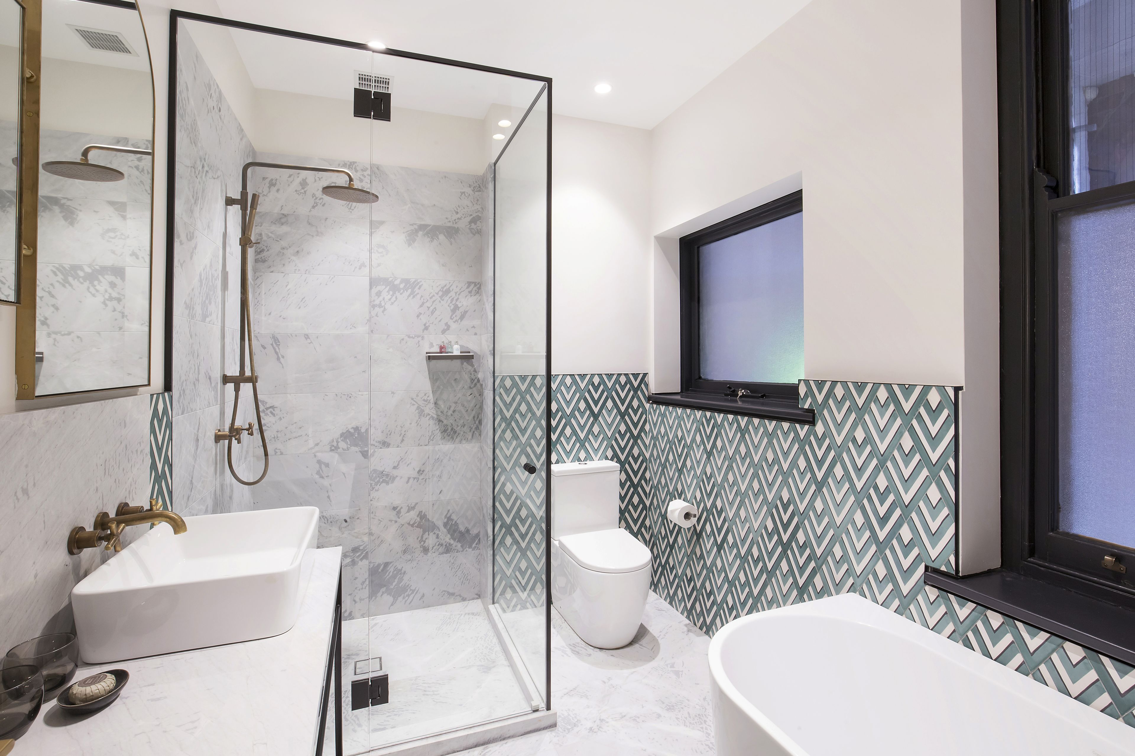 Un baño moderno con ducha envuelta en vidrio, un lavamanos blanco, inodoro y bañera.