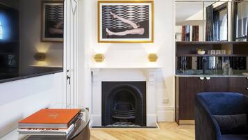 Una sala de estar moderna con chimenea, libros y un sillón azul.