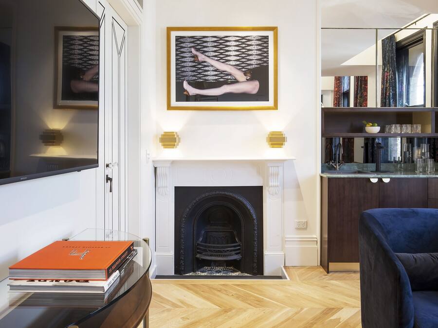 Una sala de estar moderna con chimenea, libros y un sillón azul.