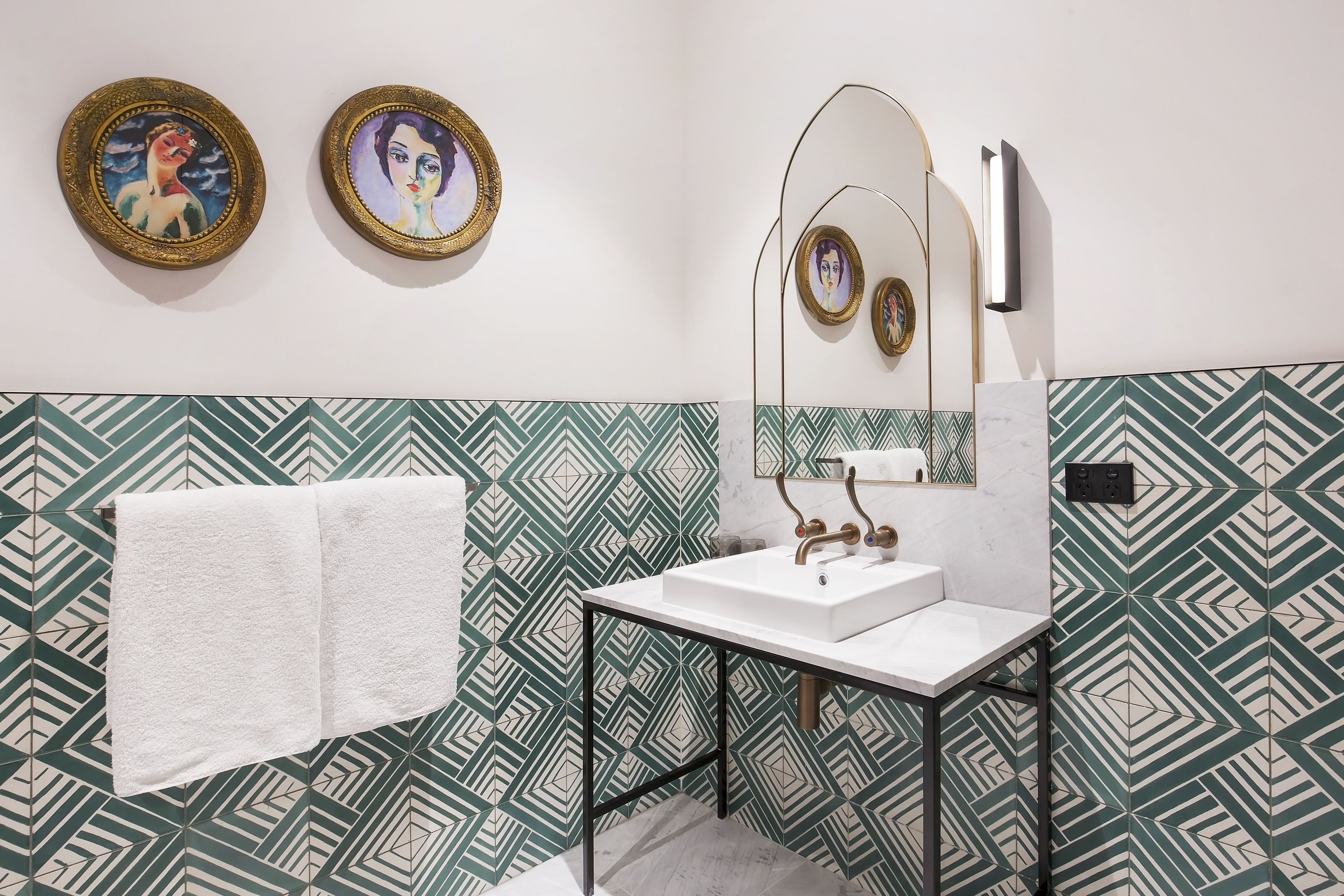Un baño con lavamanos blanco, toallero y papel tapiz estampado.