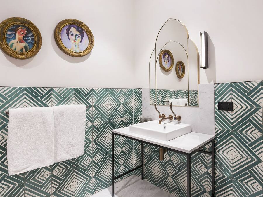 Un baño con lavamanos blanco, toallero y papel tapiz estampado.