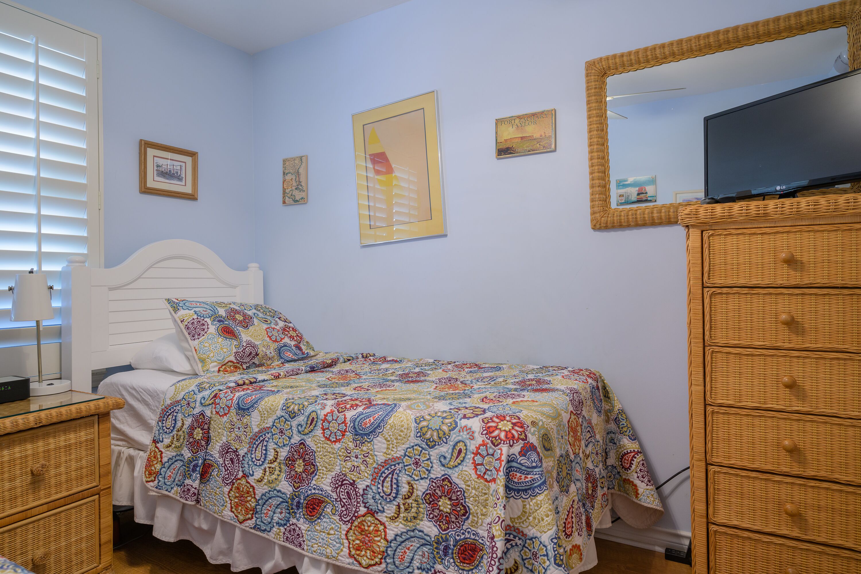A bedroom with a bed, a dresser, a television, and wall decorations.