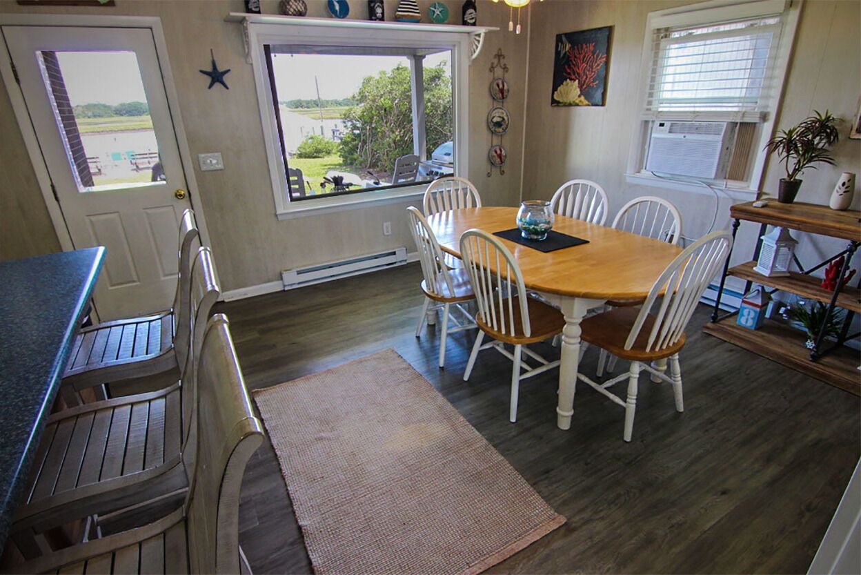 A dining area with a wooden table and white chairs, a window with a view, and a star decoration on the wall.