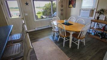 A dining area with a wooden table and white chairs, a window with a view, and a star decoration on the wall.