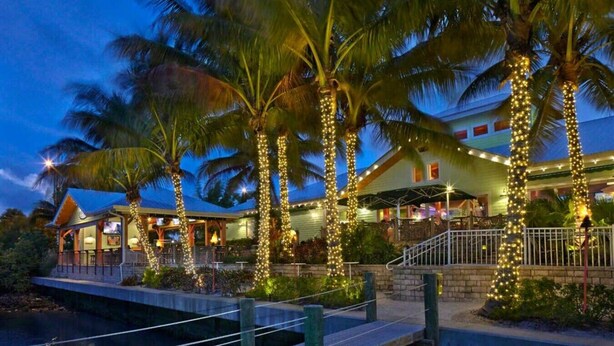 A waterfront property with palm trees, a dock, and a building with outdoor seating. - Boho Charm, Historic 1br -Steps to downtown (Melbourne)