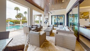 Un vaste espace de détente extérieur, aménagé avec des meubles en osier, une piscine et offrant une vue sur les palmiers.