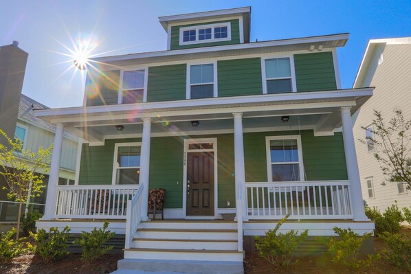 A two-story house with a front porch, a front door, and a mailbox.