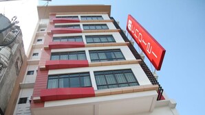 Un hotel de varios pisos con fachada roja y blanca, balcones y un letrero llamativo.