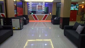 Un hall con sofás, un mostrador de recepción y un letrero grande iluminado.