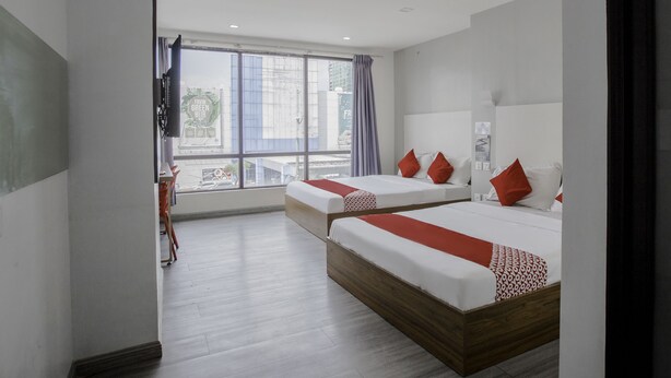 Habitación de hotel con dos camas, un ventanal grande y vistas a la ciudad.