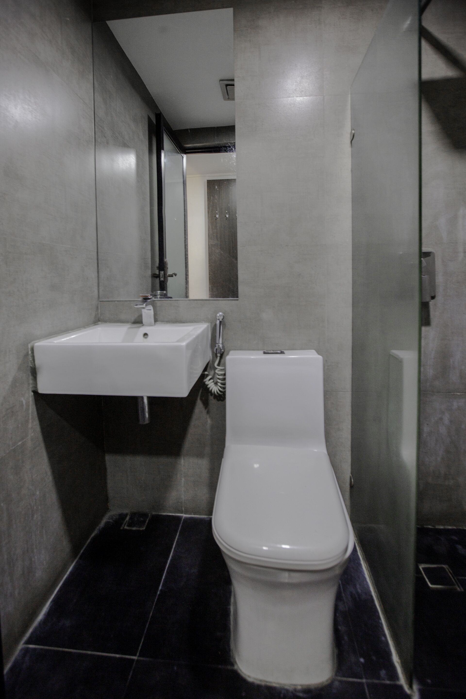 A modern bathroom with a white sink, a toilet, and a mirror.