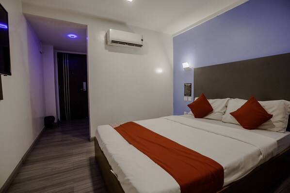 A hotel room with a large bed, a headboard, an air conditioning unit, and a door leading to another room. - Mc Hotel Fairview (Quezon City)