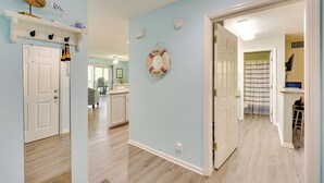 Un couloir avec un mur bleu clair, un plancher en bois, une porte blanche et un élément de décoration représentant un cercle de sauvetage.