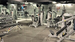 Un gimnasio con diverso equipo de ejercicio, incluyendo mancuernas, cintas de correr y máquinas de pesas.