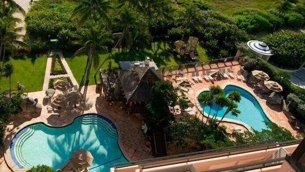 Un resort con piscina, playa y palmeras.