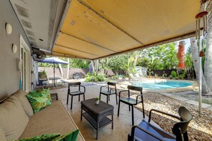 Un espace extérieur aménagé avec une terrasse, une piscine, des sièges couverts et un ventilateur.