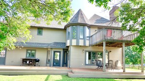 A two-story house with a covered porch, a grill outside, and a well-maintained lawn. - WOW ~ Watch the Sun Set from your Private Balcony ~ Family Gatherings  (Topeka)