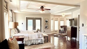 A spacious bedroom with a large bed, a ceiling fan, and a view of the outdoors through a door. - WOW ~ Watch the Sun Set from your Private Balcony ~ Family Gatherings  (Topeka)
