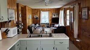 A cozy cabin interior with a kitchen, dining area, and living room. - Screened porch, Lake Huron views, quiet sub, walk to beach and town in minutes! (Port Austin)