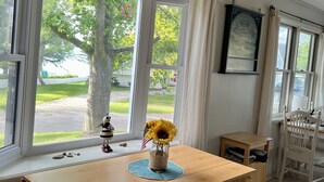 A room with a wooden table, a vase with sunflowers, a small American flag, and a decorative item resembling a bee. - Screened porch, Lake Huron views, quiet sub, walk to beach and town in minutes! (Port Austin)
