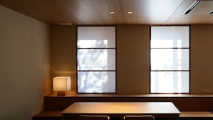 A room with a wooden table, benches, and a window with a view of trees. - Hotel Sanraku (Yamanouchi)